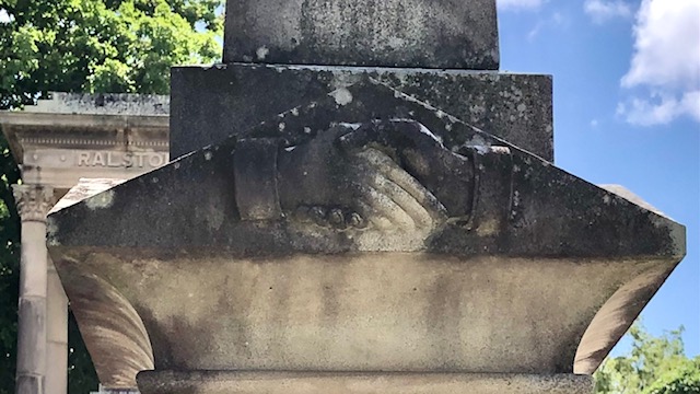 Headstone carving with men shaking hands